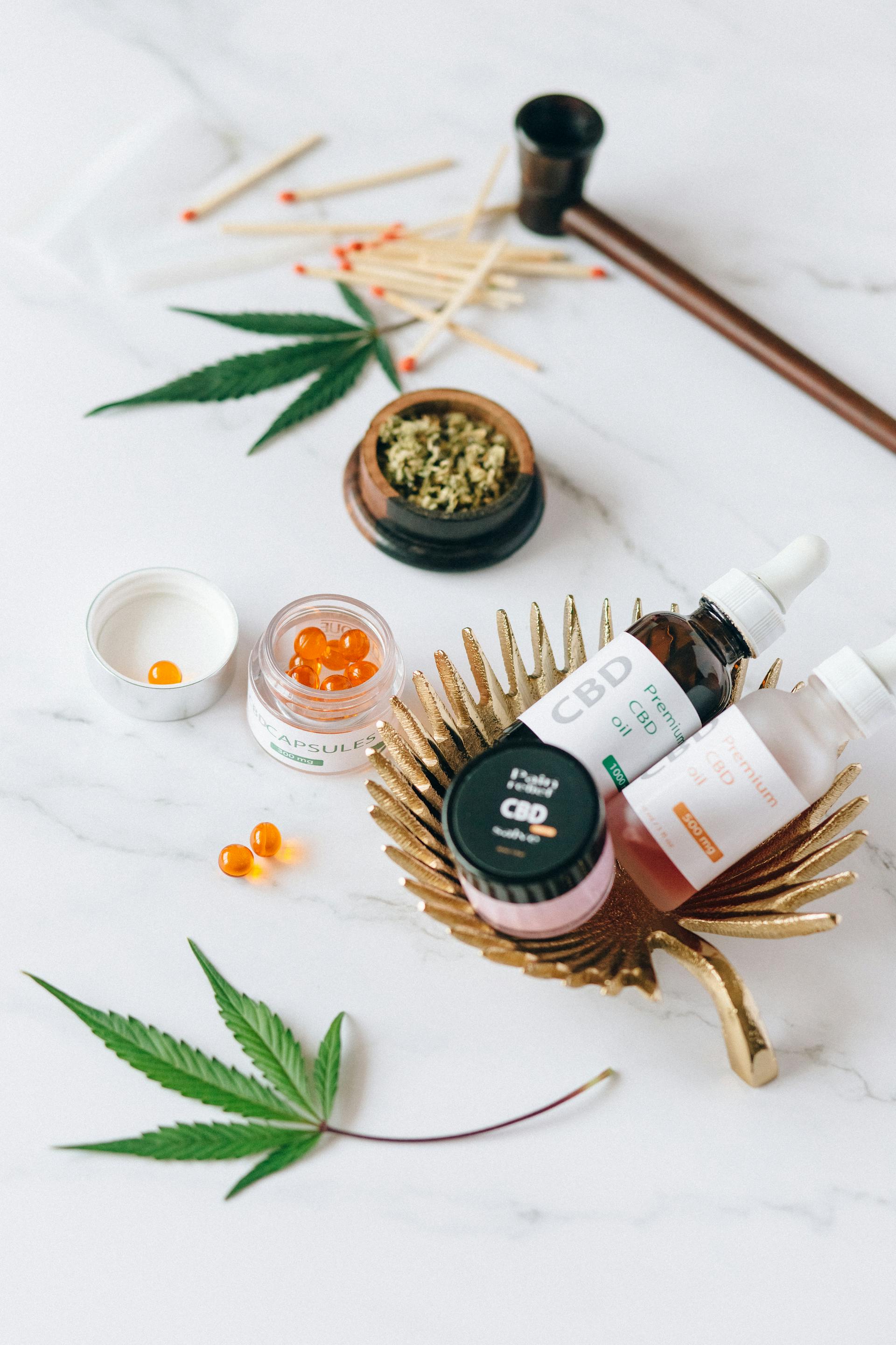 Cannabis leaves, a grinder, and curated botanical items arranged in a bright editorial flat lay.